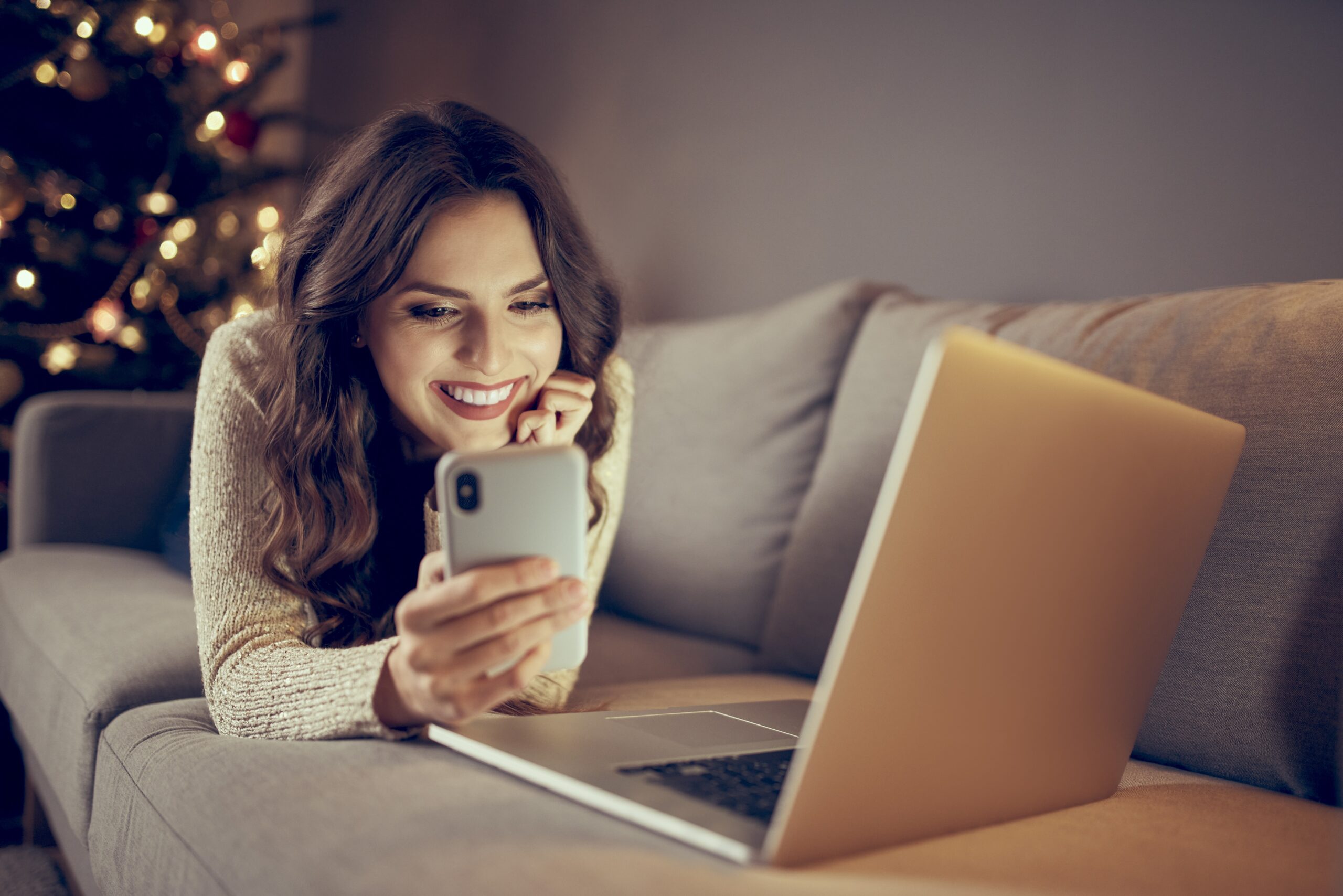 Beautiful young woman paying with mobile phone for online shopping ordering Christmas presents